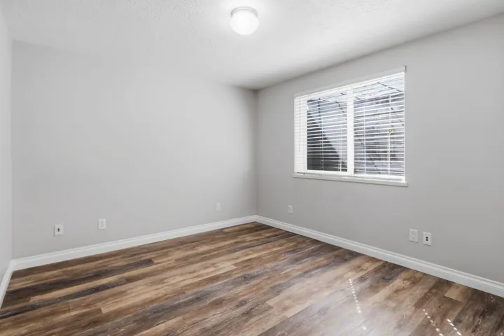 Wood-finish flooring, light grey wall paint, and a window with horizontal blinds