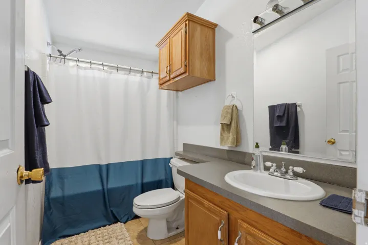 Spa-inspired bathroom featuring a dual-sink vanity with wood-finish cabinetry and concrete countertops, ceramic vessel sink, polished chrome fixtures, and recessed lighting