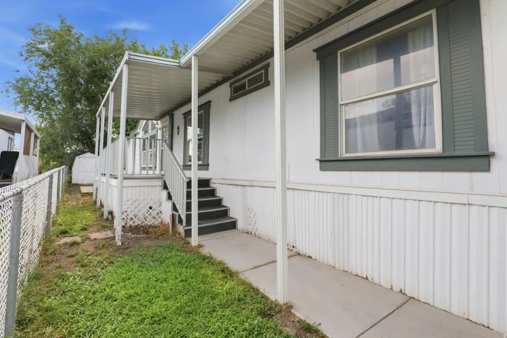 Welcoming front entry featuring a covered porch with white railings, composite decking, and metal support posts