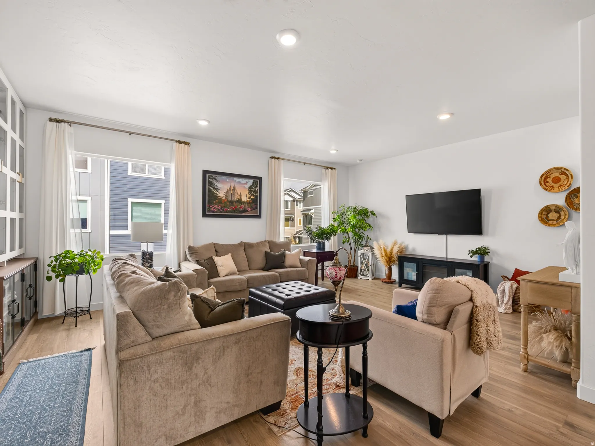 Recessed lighting, light wood-finish flooring, white walls, multiple windows, and built-in cabinetry with glass panels