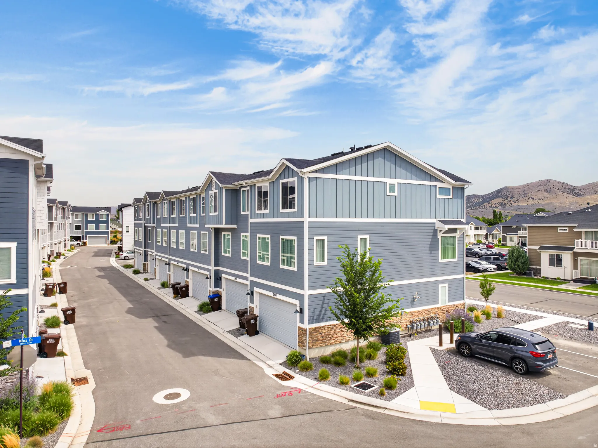 Modern townhome exterior with mixed siding, stone accents, and an attached garage