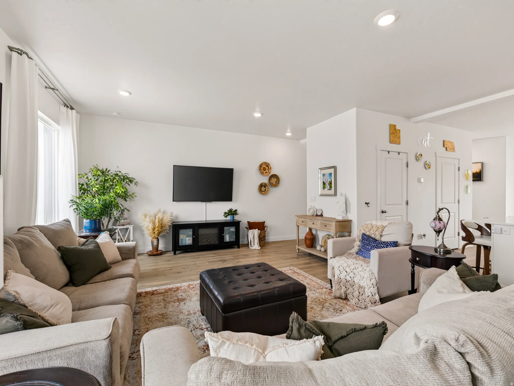 Open-concept living space featuring wood-finish flooring, recessed lighting, and white walls