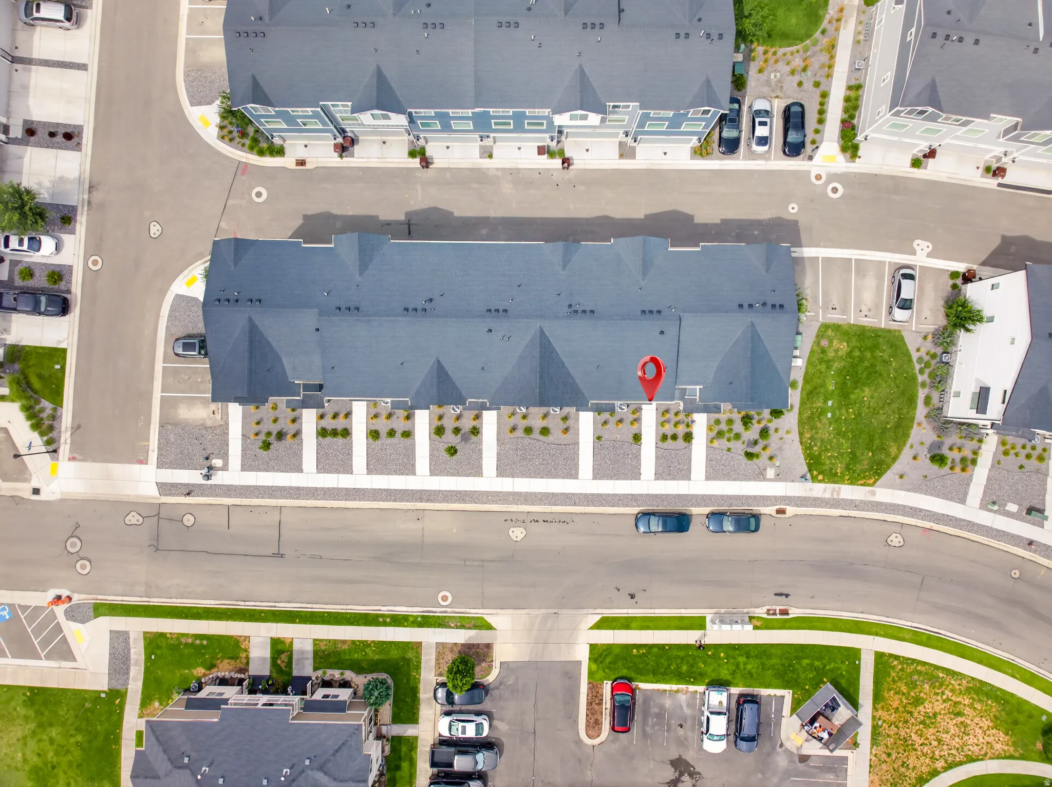 Townhome property featuring a dark-toned roof and structured landscaping