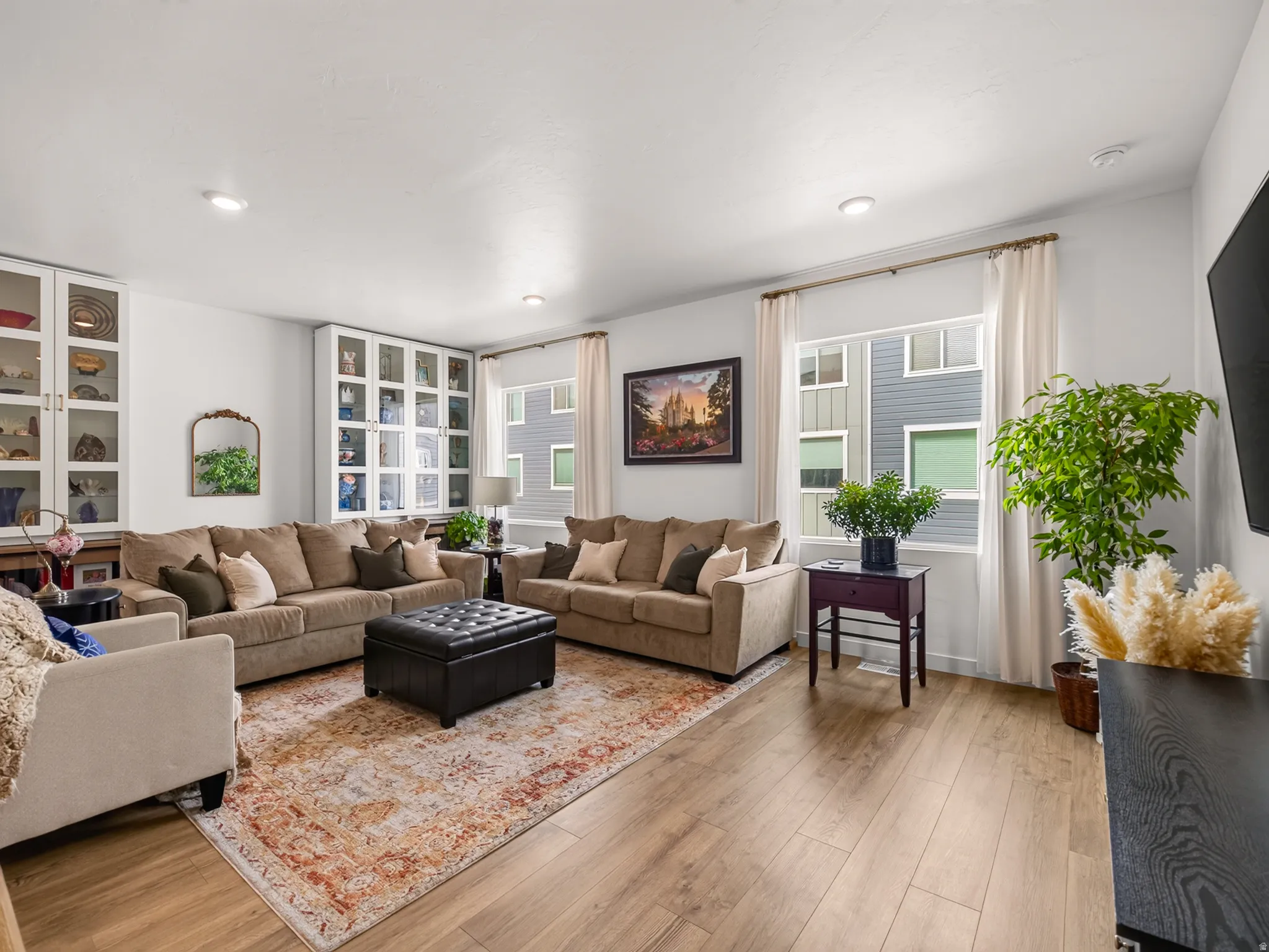 Recessed lighting, wood-finish flooring, two built-in glass-front display cabinets, and large windows