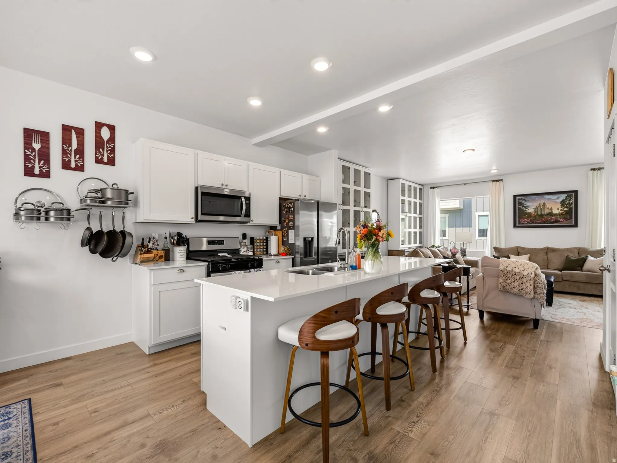Open-concept kitchen featuring an island with seating, stainless steel appliances, recessed lighting, and wood-finish flooring