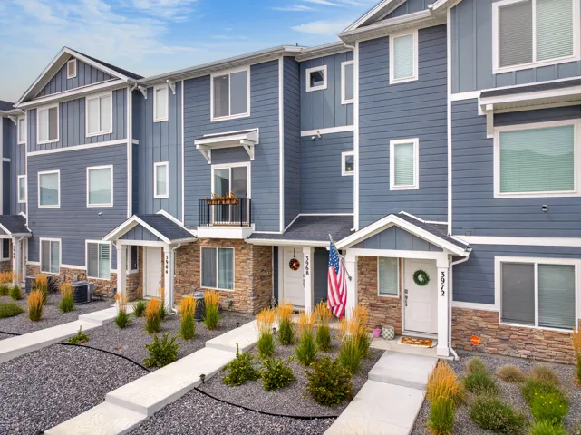 Modern townhome exterior featuring blue siding, white trim, stone accents, and multiple windows