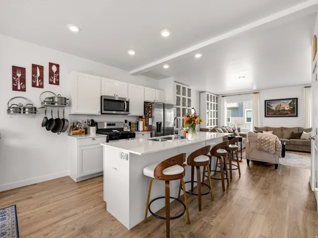 Open-concept kitchen featuring an island with seating, stainless steel appliances, recessed lighting, and wood-finish flooring