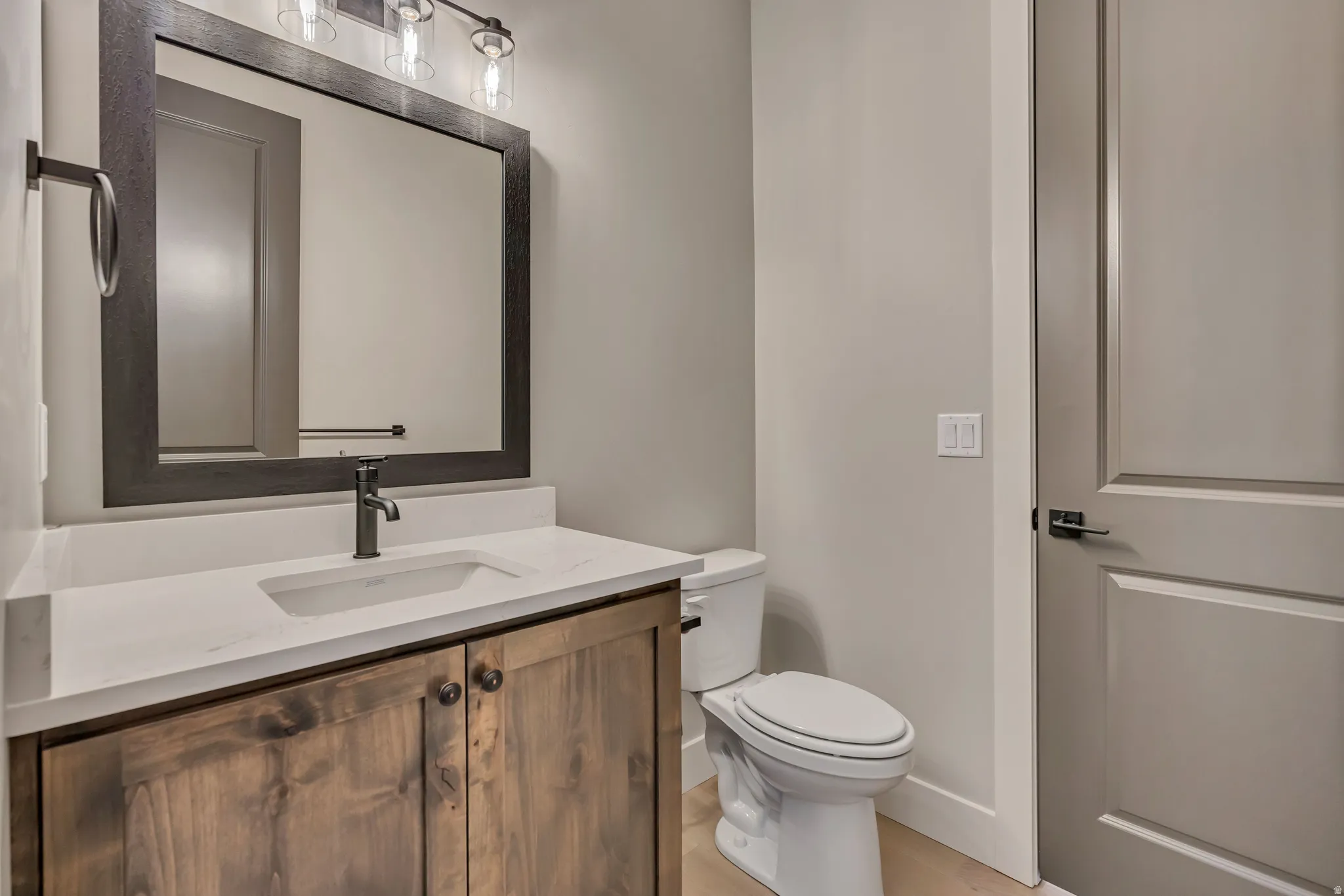 Vanity with wood-finish cabinetry, integrated sink, and white countertop
