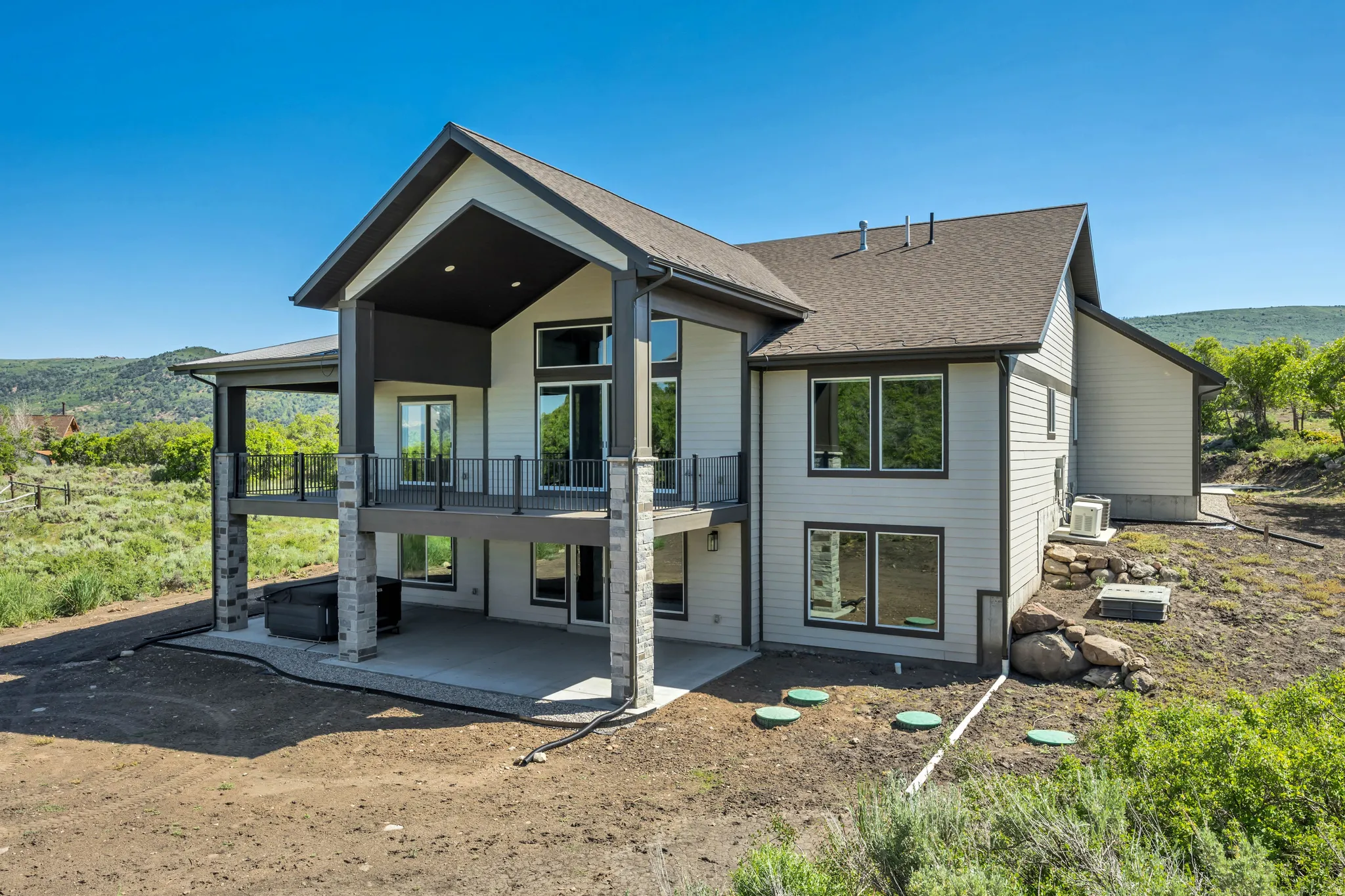 Contemporary exterior with multiple balconies and patios, stone columns, and large windows