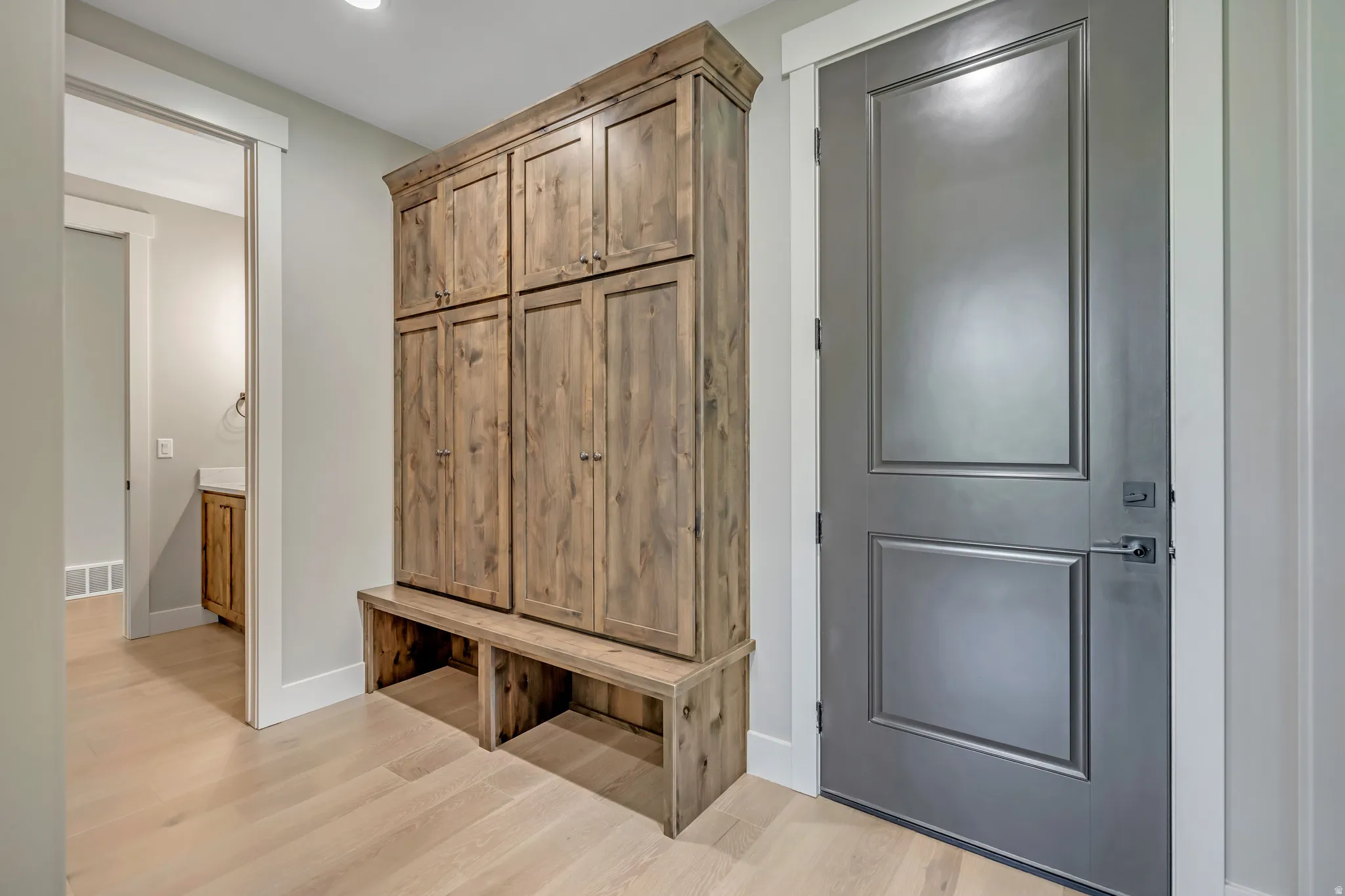 Built-in wood-finish storage cabinetry with a bench