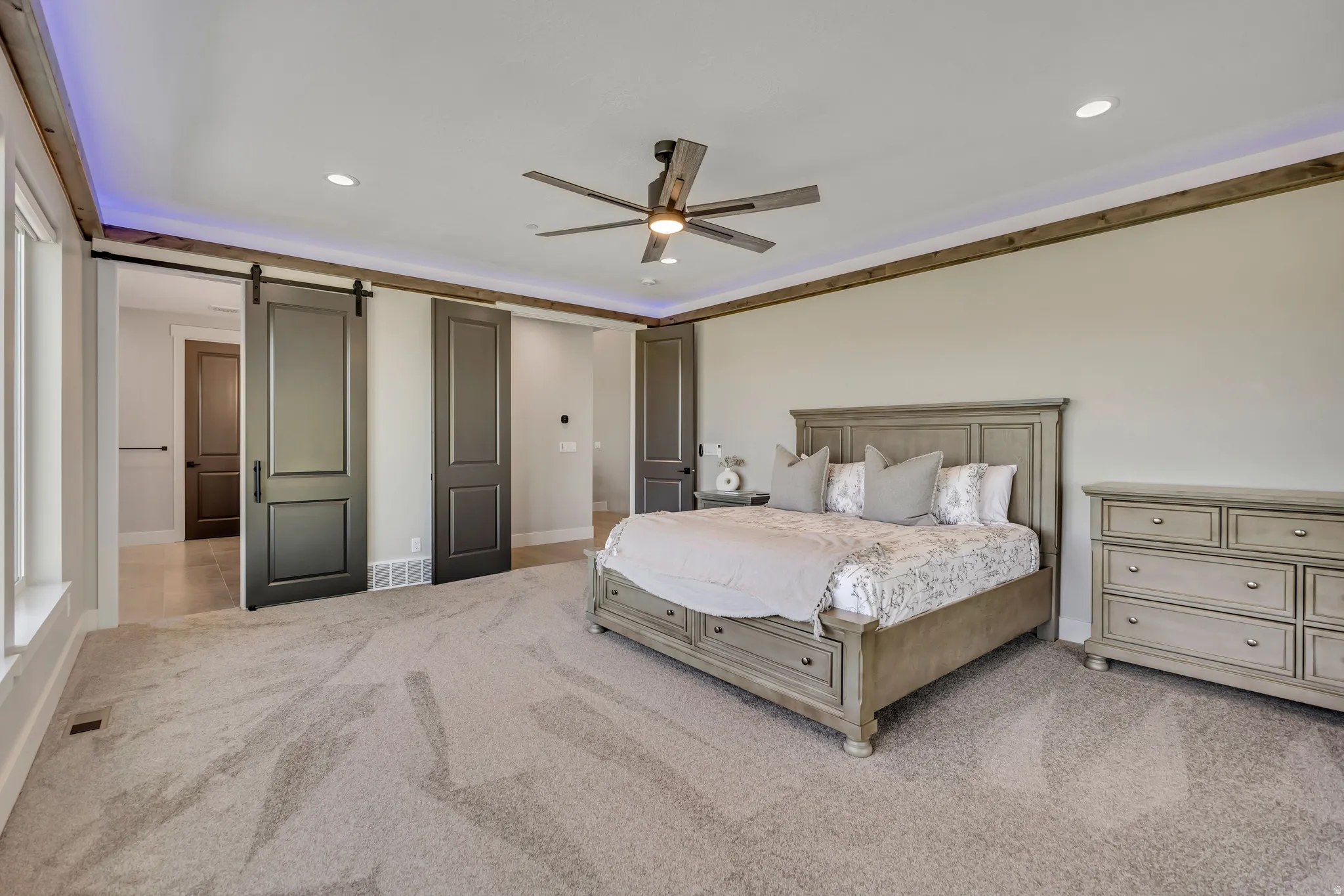 Recessed lighting, wood-finish ceiling trim, and a ceiling fan with integrated lighting