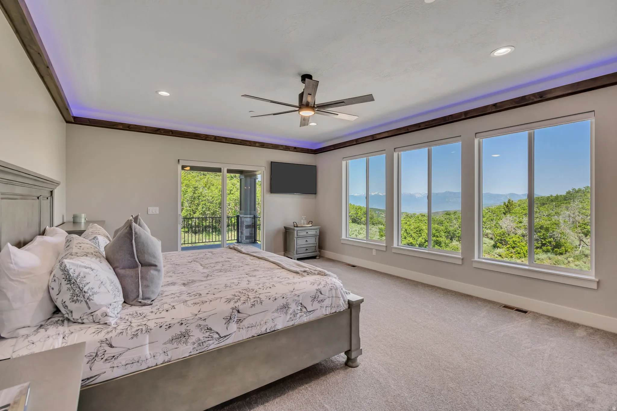 Expansive room with recessed lighting and a ceiling fan, featuring three large windows and a sliding glass door