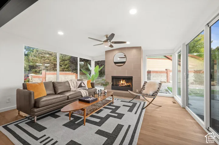 Wood-finish flooring, recessed lighting, and a corner fireplace with a stone surround