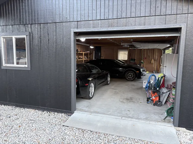 Detached garage with dark panel siding, a single window, and a roll-up garage door
