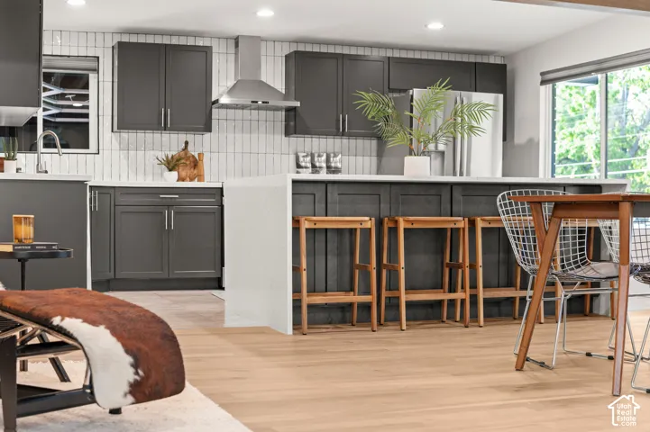 Kitchen with dark grey cabinetry, white countertops, and a full-height tiled backsplash