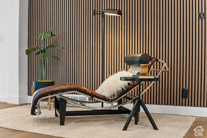 Wood-slatted accent wall, wood-finish flooring, white wall trim, and a wall-mounted control panel