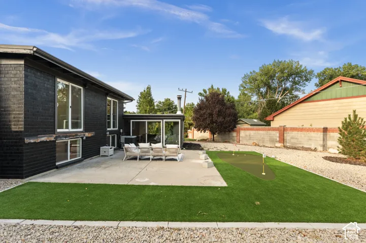 Expansive concrete patio with direct access to a putting green, artificial turf, and a gravel perimeter