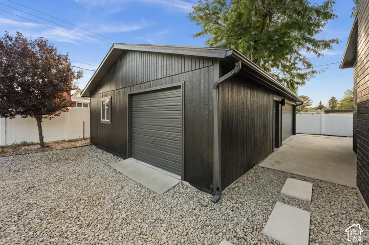 Detached garage with dark vertical siding, a roll-up garage door, and a concrete approach