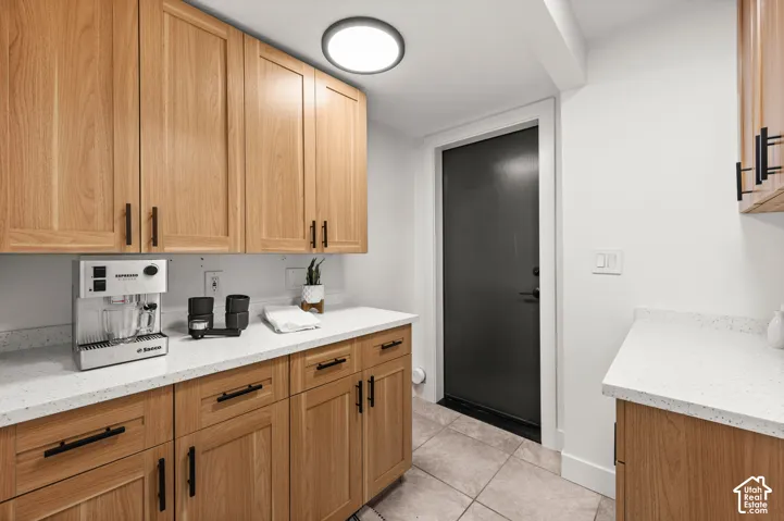Wood-finish cabinetry with black hardware, white speckled countertops, and ceiling-mounted light fixture