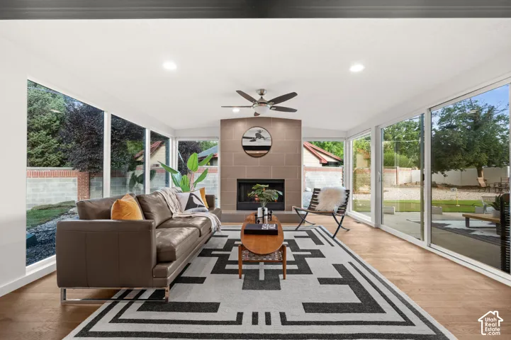 Living area featuring full-height windows, wood-finish flooring, a contemporary fireplace, and recessed lighting