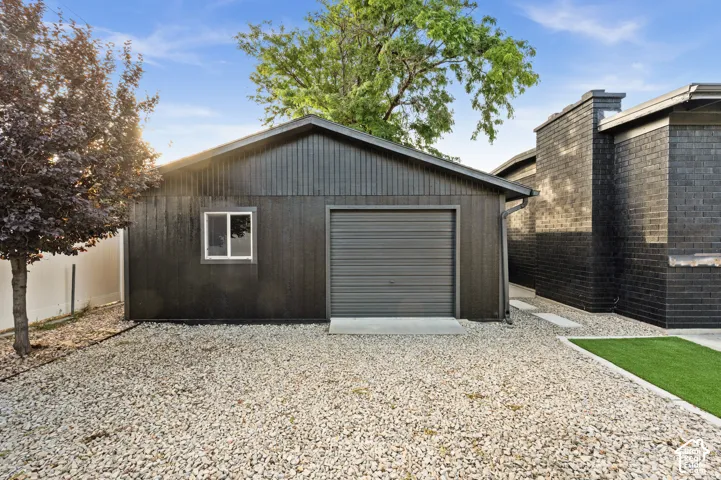 Detached garage with a roll-up door, side window, and gravel landscaping