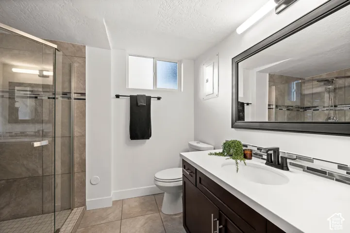 Glass-enclosed shower with tiled surround, wood-finish vanity with countertop, rectangular undermount sink, and large framed mirror