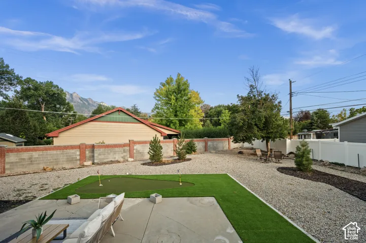 Expansive backyard featuring a putting green, concrete patio, gravel landscaping, and a privacy fence