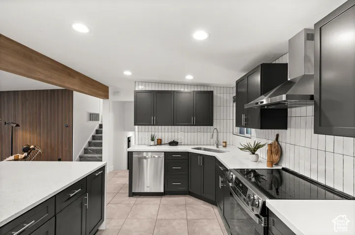 Kitchen featuring dark cabinetry, stainless steel appliances, white countertops, and a white tile backsplash