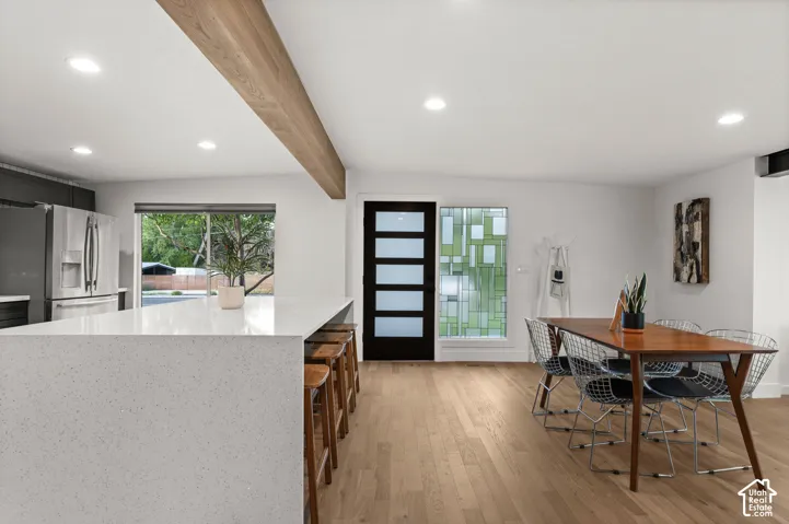 Open-concept living space with light wood-finish flooring, a wood-finish ceiling beam, and recessed lighting