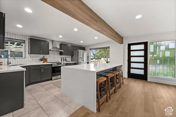 Modern kitchen featuring dark cabinetry, stainless steel appliances, a center island with countertop seating, and a decorative stained glass window