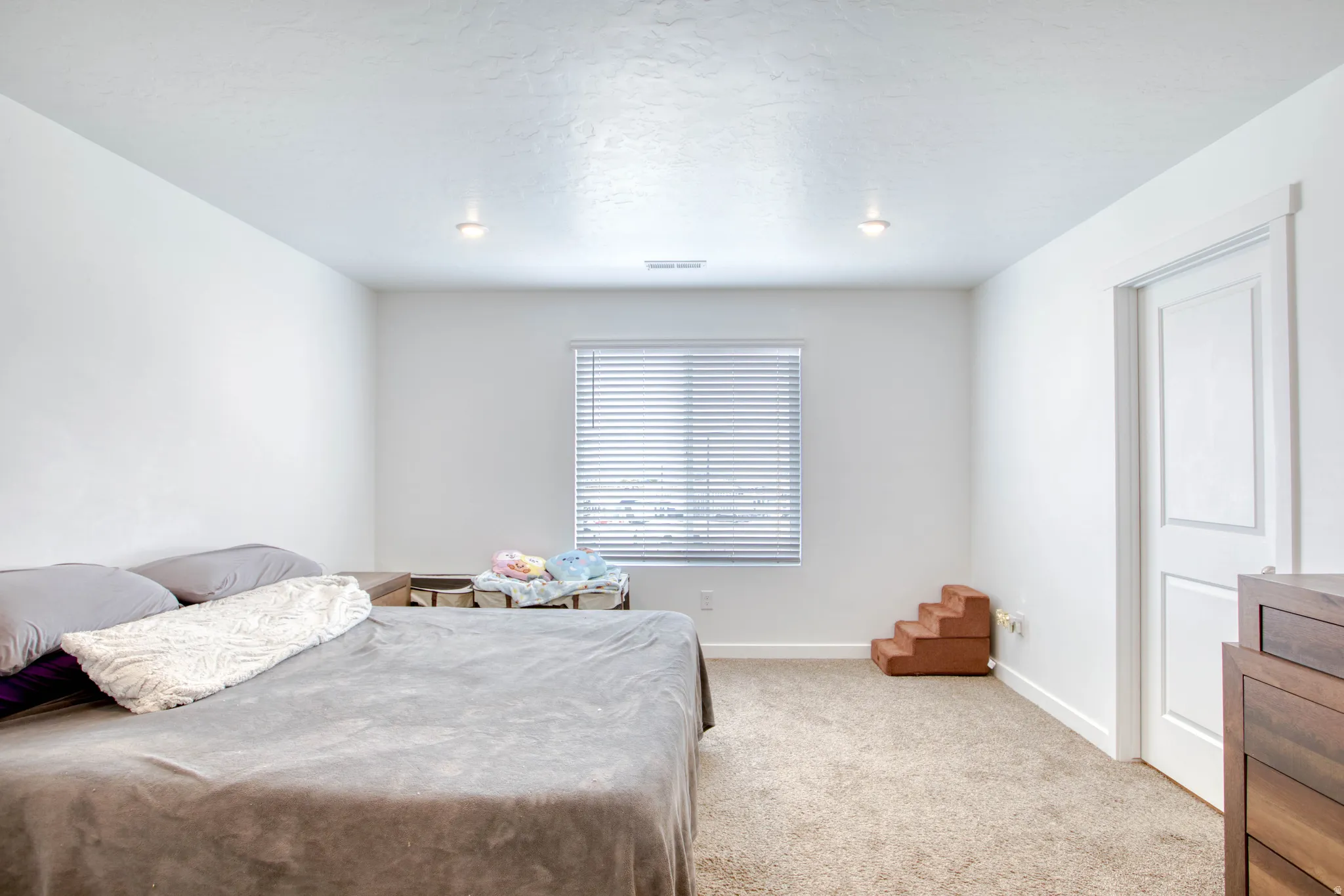 Recessed lighting, neutral-toned carpeting, white walls, white trim, and a window with blinds