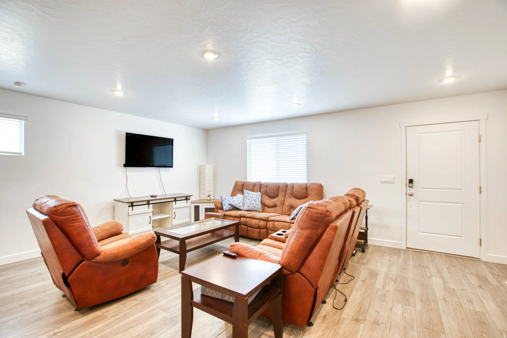 Recessed ceiling lighting, wood-finish flooring, white paneled door, and white walls