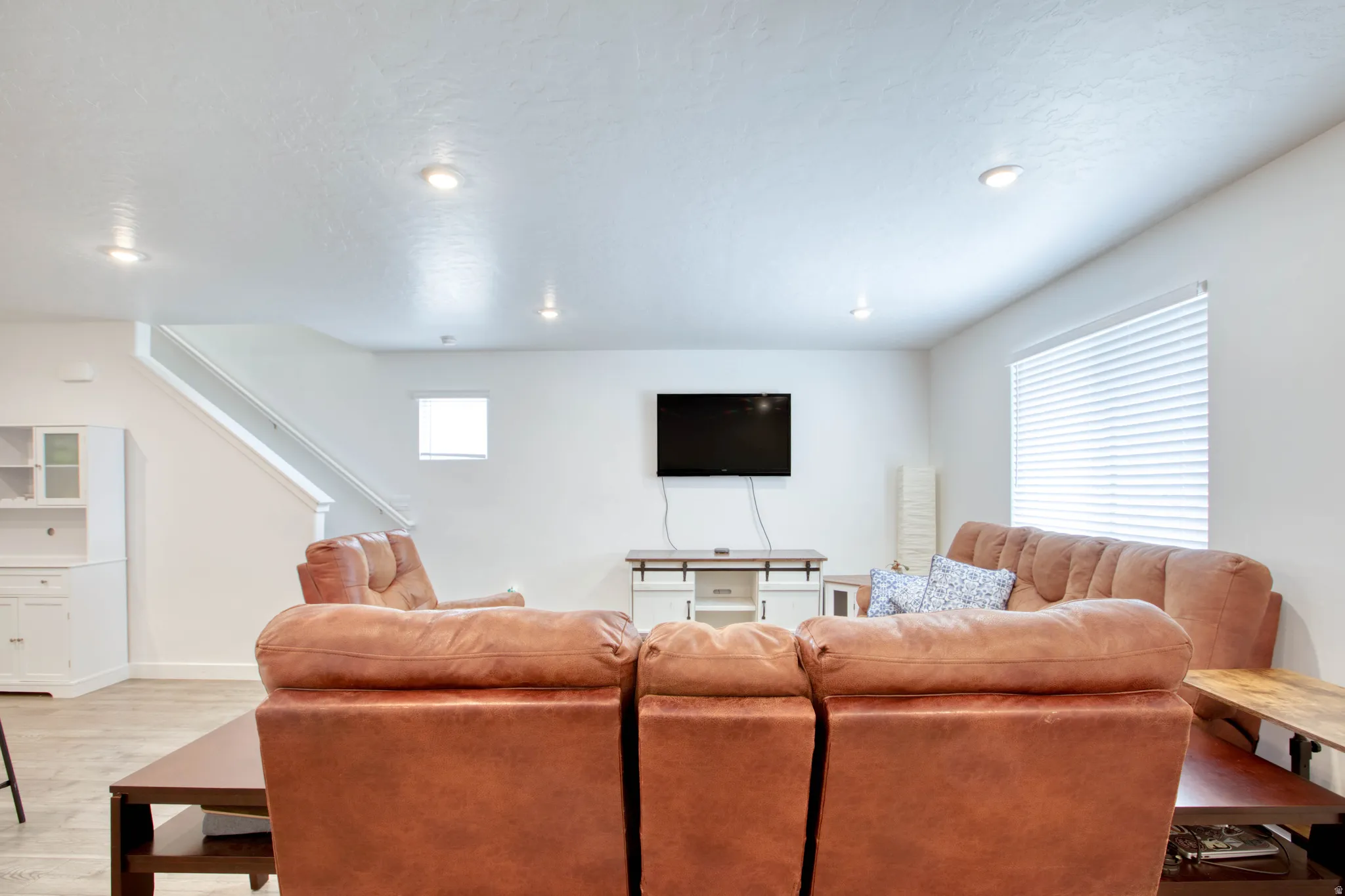Recessed ceiling lighting, wood-finish flooring, built-in cabinetry, staircase with white railing, and window with blinds
