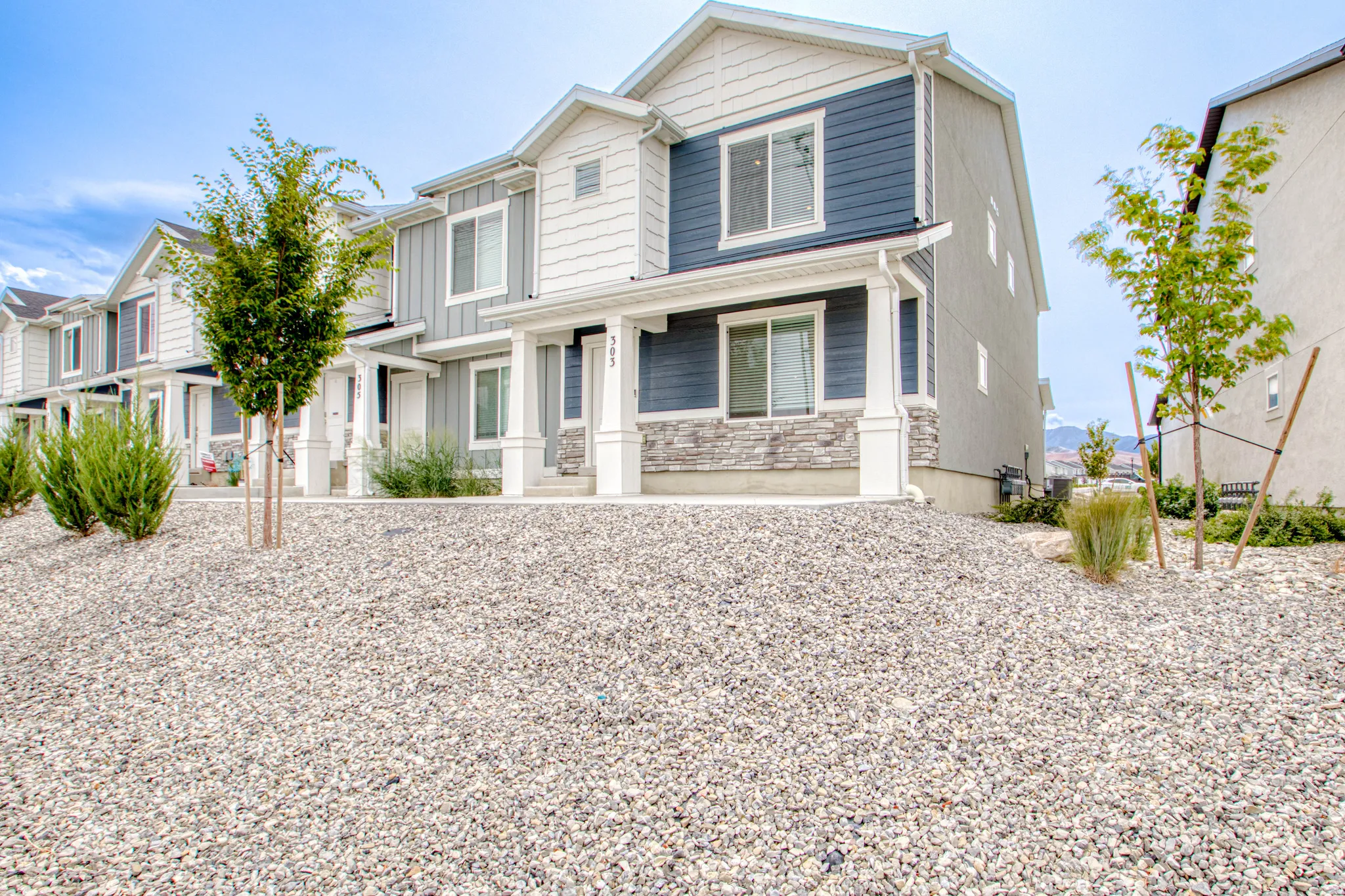 Contemporary multi-level residence featuring a covered entry, columned porch, and stone facade accents