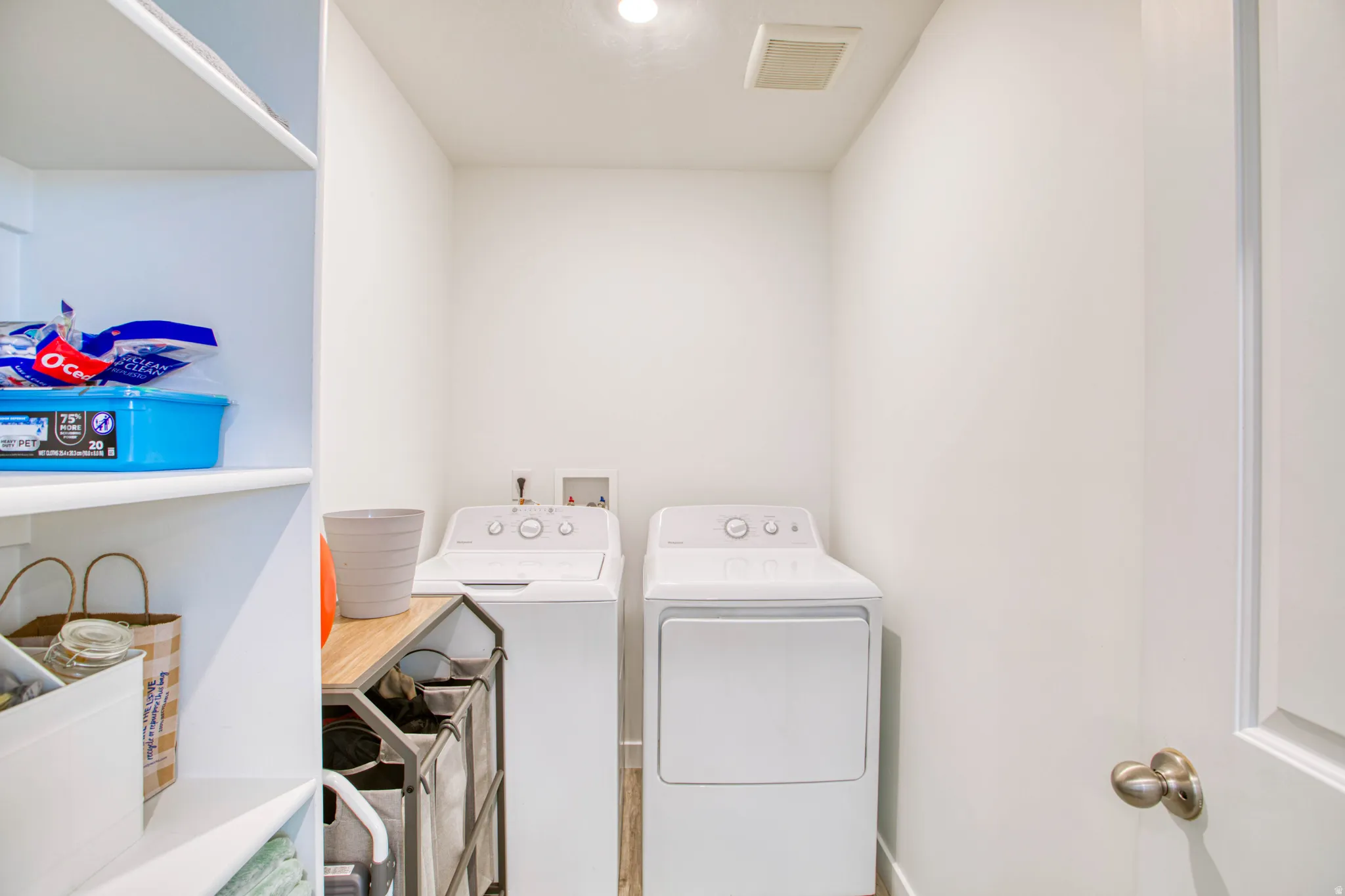 Dedicated laundry area featuring a top-load washing machine, front-load dryer, and adjacent built-in shelving