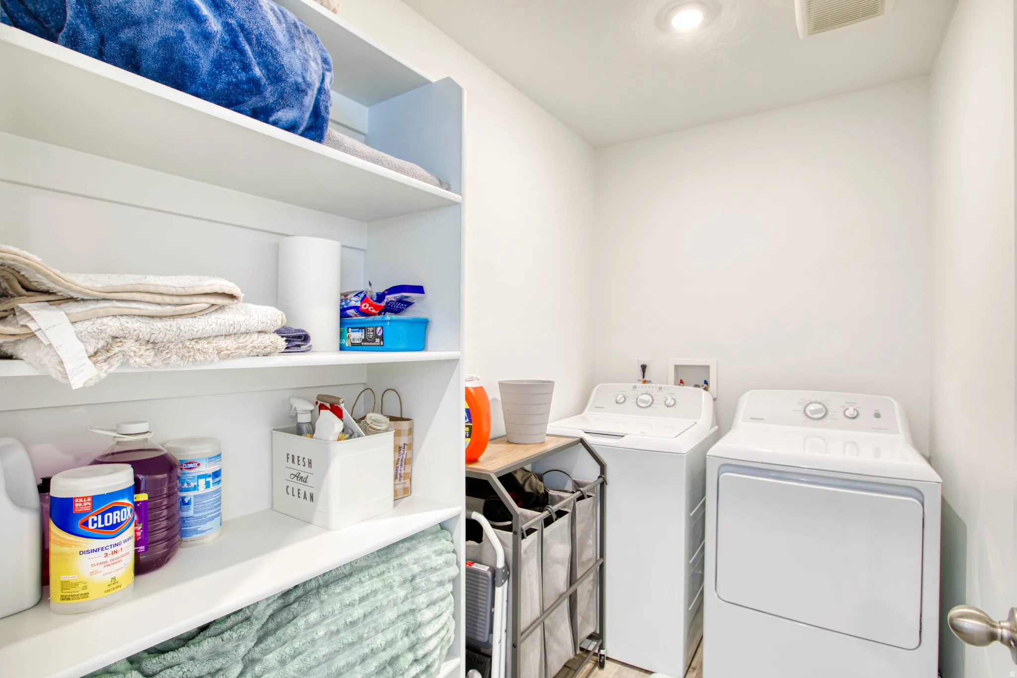 Dedicated laundry area with built-in shelving, overhead lighting, and a neutral color palette