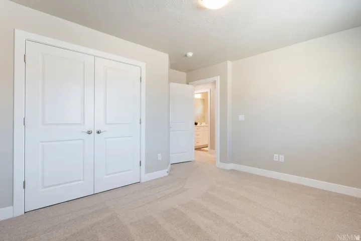 Neutral tone walls, light carpeting, white trim, and a flush-mount ceiling light fixture