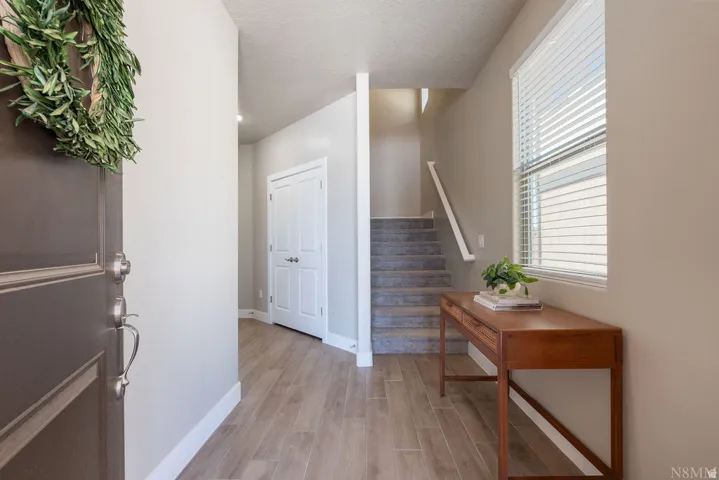 Entryway featuring wood-finish flooring, a window with blinds, and a carpeted staircase