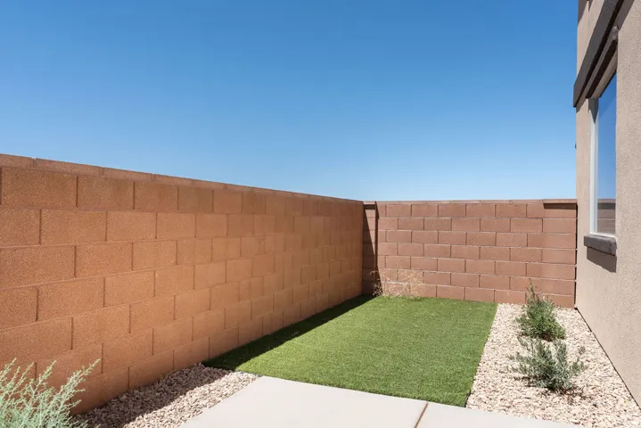 Enclosed patio area featuring concrete block walls, a section of artificial turf, and gravel landscaping
