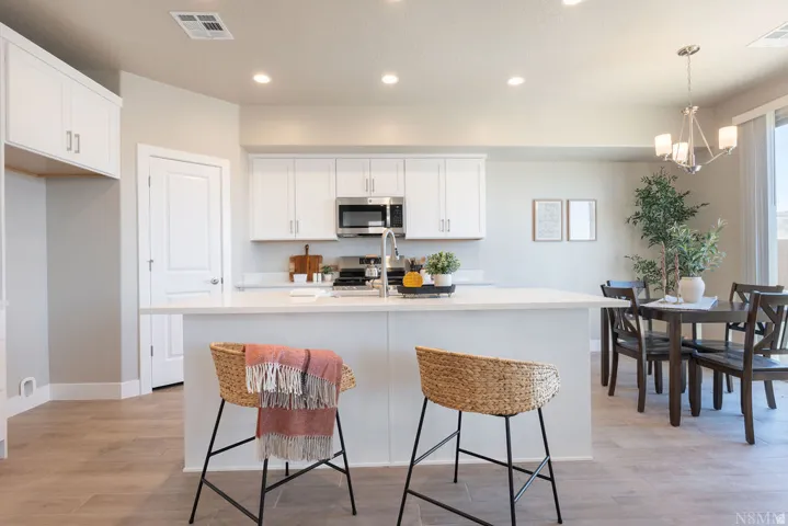 Open-concept kitchen with white cabinetry, stainless steel appliances, a center island, recessed lighting, and wood-finish flooring