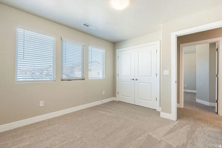 Neutral tone wall paint, carpeted flooring, three windows with blinds, double-door closet, and recessed lighting