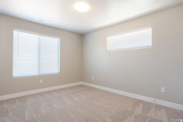 Neutral wall paint, plush carpet, two windows with blinds, and recessed ceiling lighting