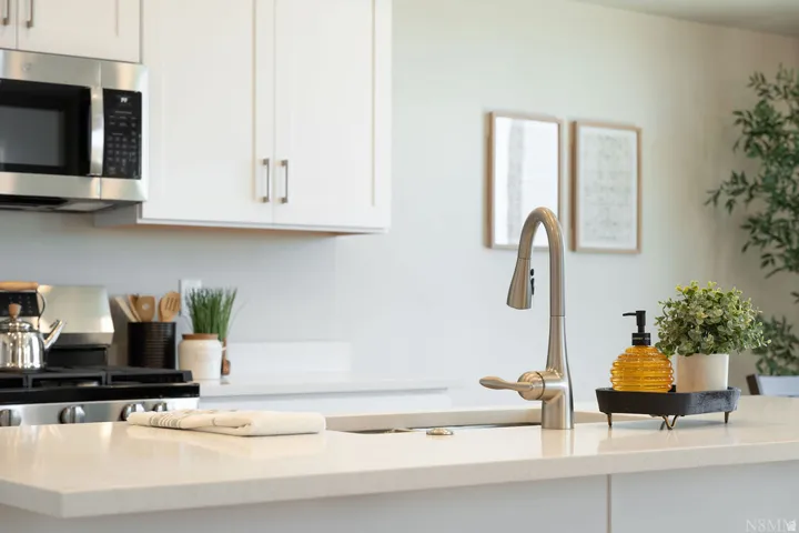 Stainless steel microwave and range, white shaker-style cabinetry, and light-toned countertops