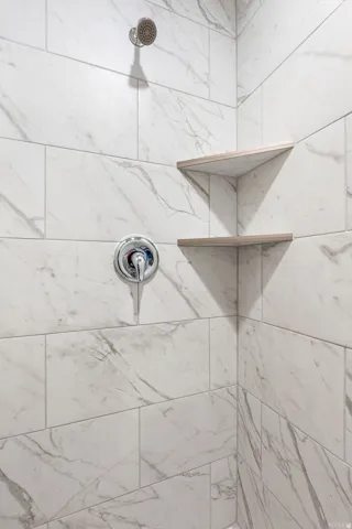 Shower with white marble-look subway tile, chrome shower head, and chrome single-handle control