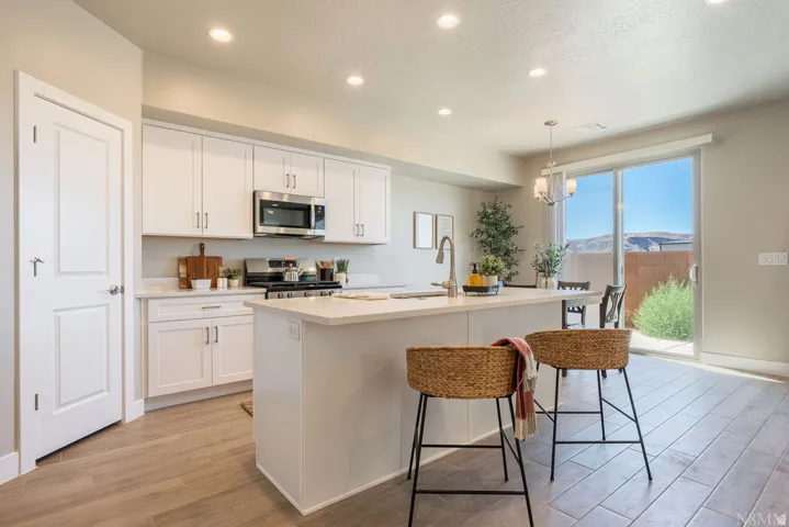 White cabinetry, stainless steel appliances, and a central island with countertop seating