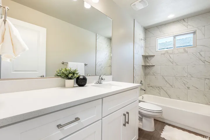 White vanity with brushed nickel hardware, expansive countertop, and large wall-mounted mirror