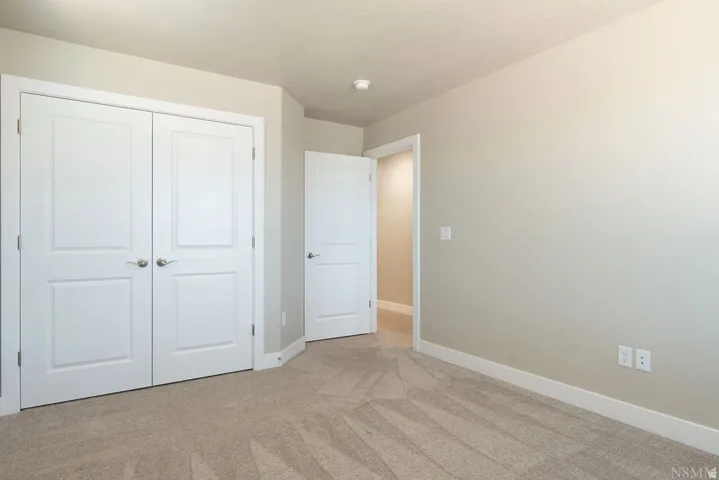 Textured carpet flooring, neutral paint palette, white trim, and white panel doors