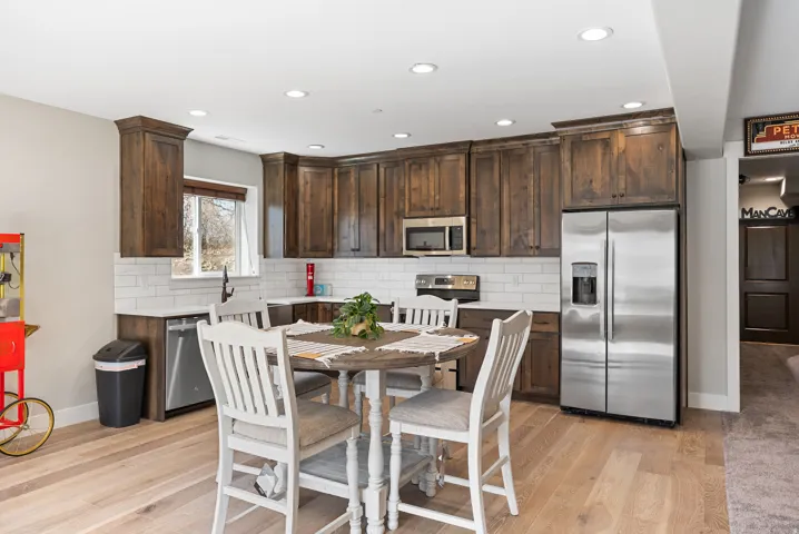 Kitchen featuring wood-finish flooring, dark wood cabinetry, white subway tile backsplash, and stainless steel appliances
