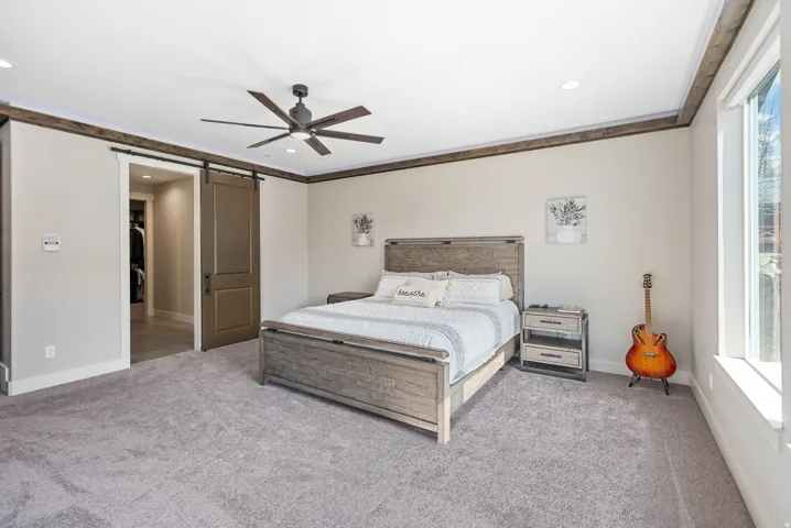 Spacious room featuring light gray carpeting, recessed lighting, a ceiling fan, and a barn door