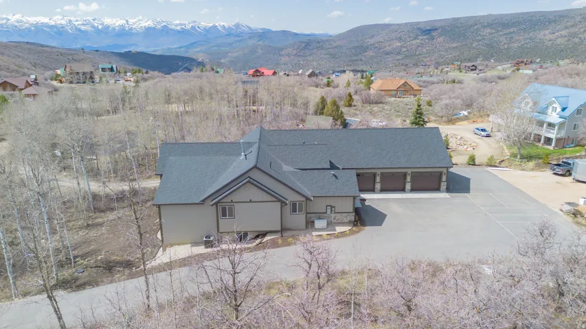 Expansive paved drive, three-car garage, stone facade accents, and a dark shingle roof